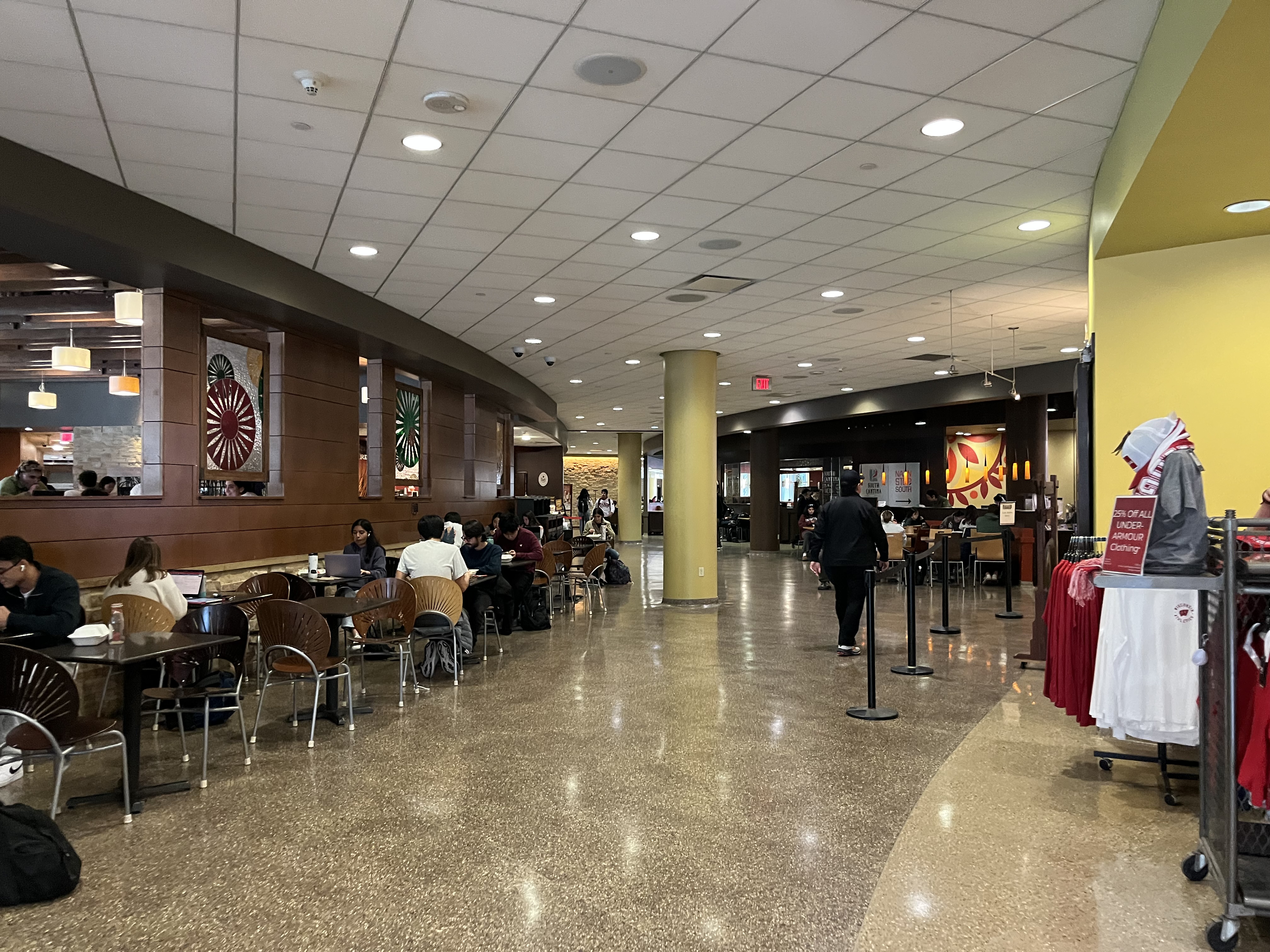 Students study inside Union South with restaurants on the right.
